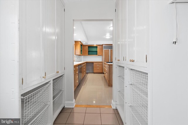 kitchen featuring dishwasher, white cabinetry, light tile patterned floors, and sink