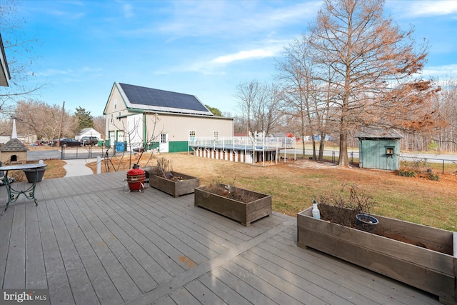 wooden terrace with a storage unit and a lawn