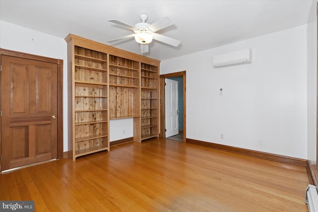 unfurnished bedroom with ceiling fan, baseboard heating, an AC wall unit, hardwood / wood-style floors, and built in desk