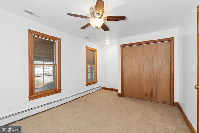 unfurnished bedroom with baseboard heating, ceiling fan, a closet, and light colored carpet