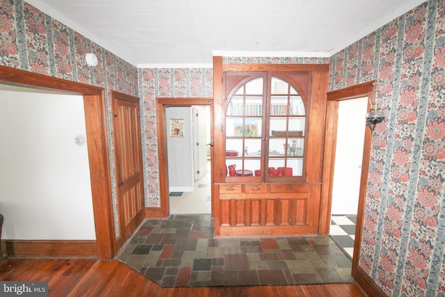 foyer with ornamental molding and dark hardwood / wood-style flooring