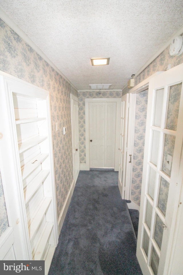 hall featuring dark carpet and a textured ceiling