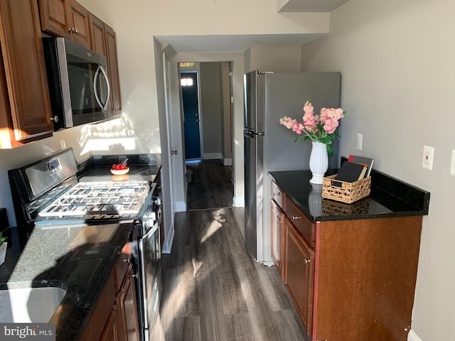 kitchen featuring dark hardwood / wood-style floors, dark stone countertops, and stainless steel appliances