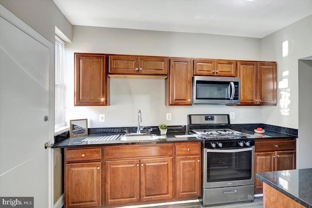 kitchen featuring appliances with stainless steel finishes, dark stone counters, and sink