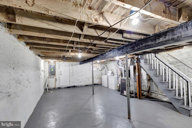 basement featuring electric panel, heating unit, and independent washer and dryer