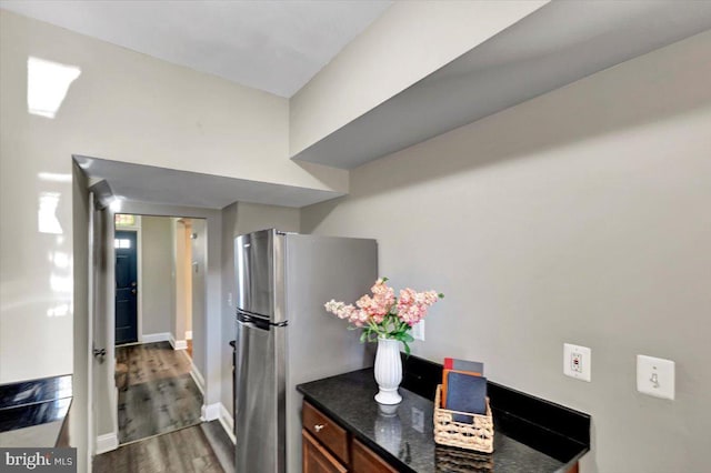 kitchen with stainless steel fridge, dark wood-type flooring, and dark stone countertops