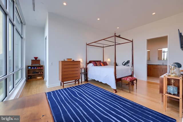 bedroom featuring light wood-type flooring, connected bathroom, and sink