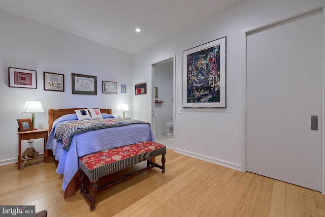 bedroom with connected bathroom and light hardwood / wood-style floors