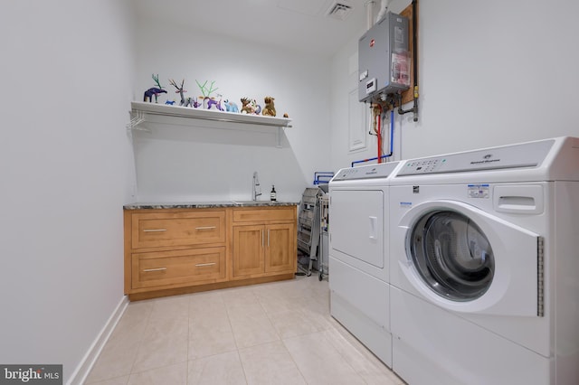 washroom featuring sink, cabinets, water heater, washer and clothes dryer, and light tile patterned floors