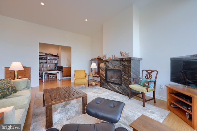 living room with a high end fireplace and light hardwood / wood-style floors