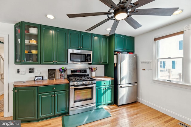 kitchen with ceiling fan, appliances with stainless steel finishes, green cabinets, and light wood-type flooring