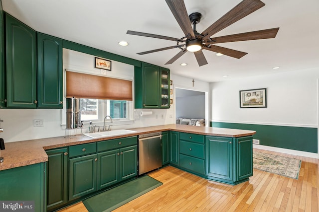 kitchen featuring sink, stainless steel dishwasher, green cabinets, and light wood-type flooring