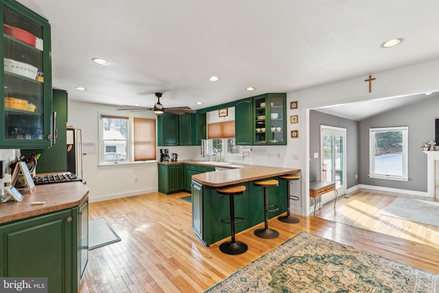 kitchen featuring green cabinets, light hardwood / wood-style floors, and a breakfast bar