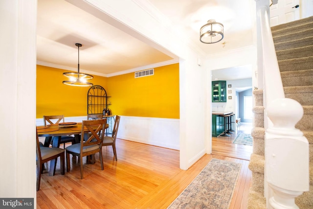 dining room featuring hardwood / wood-style floors, an inviting chandelier, and crown molding