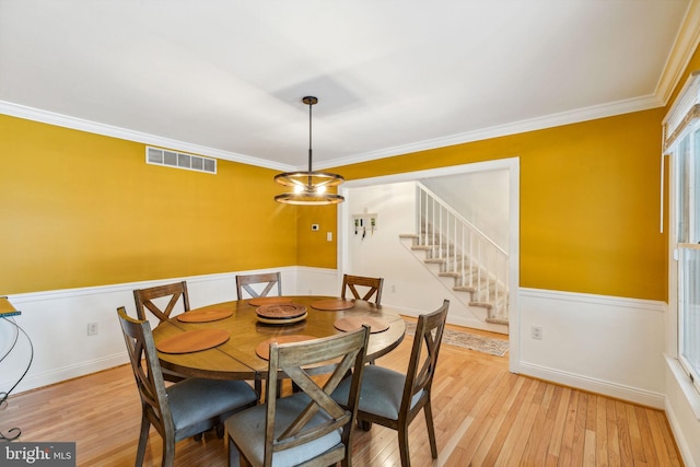 dining space featuring light wood-type flooring, a chandelier, and crown molding