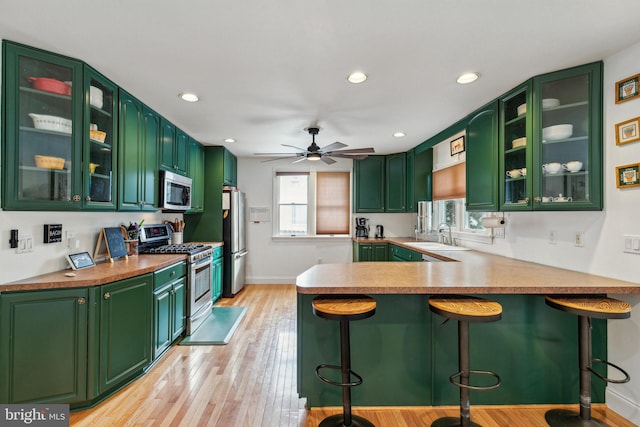 kitchen featuring kitchen peninsula, green cabinets, and appliances with stainless steel finishes