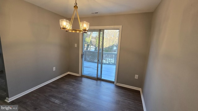 spare room with dark hardwood / wood-style flooring and a notable chandelier