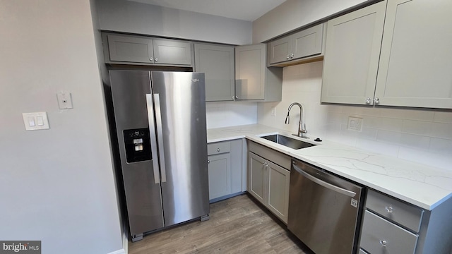 kitchen with gray cabinets, light stone counters, sink, and stainless steel appliances