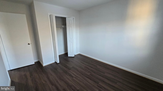 unfurnished bedroom with a closet and dark wood-type flooring