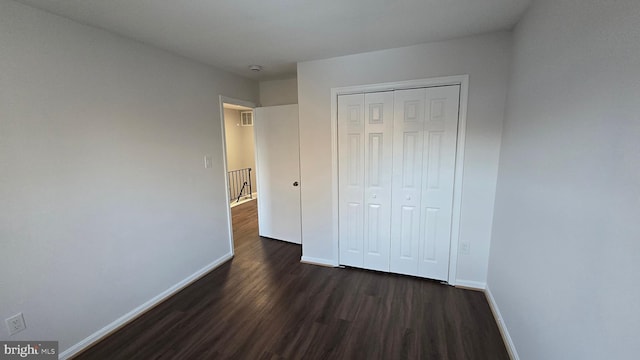 unfurnished bedroom featuring dark hardwood / wood-style flooring and a closet