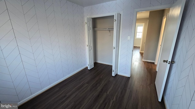 unfurnished bedroom featuring dark wood-type flooring and a closet