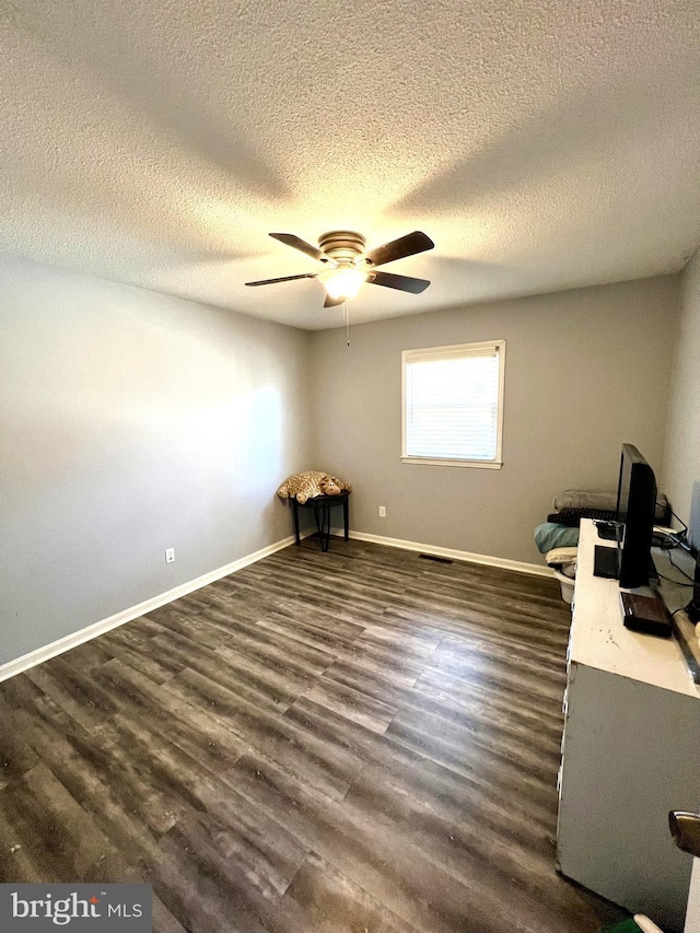 unfurnished office featuring a textured ceiling, ceiling fan, and dark hardwood / wood-style floors