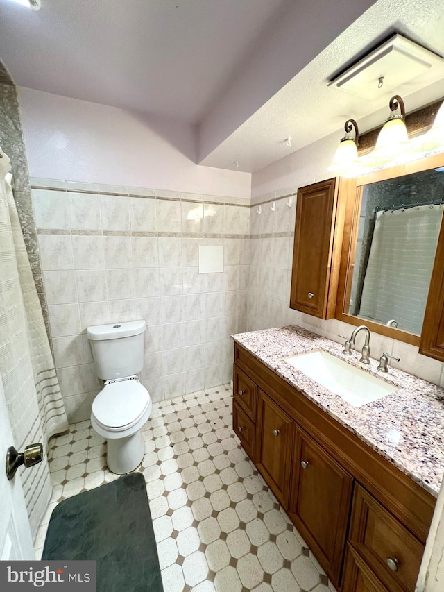 bathroom featuring vanity, toilet, tile walls, and walk in shower