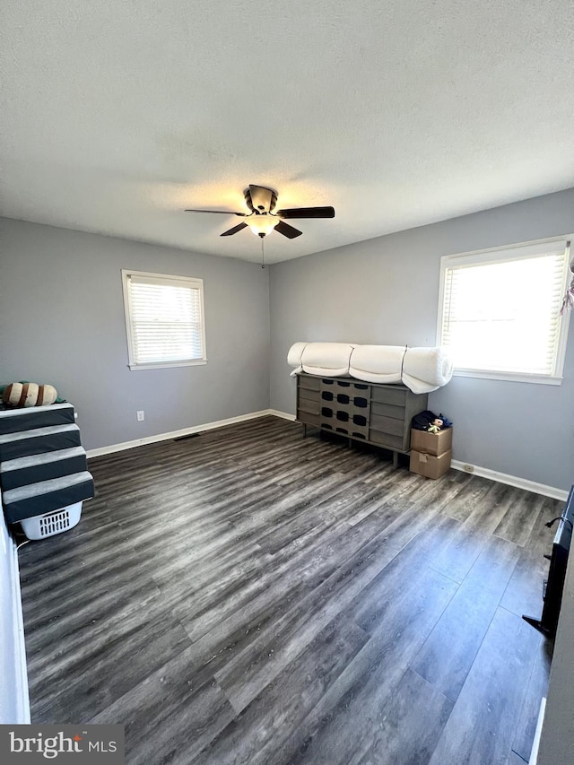 unfurnished bedroom featuring ceiling fan, dark wood-type flooring, and a textured ceiling