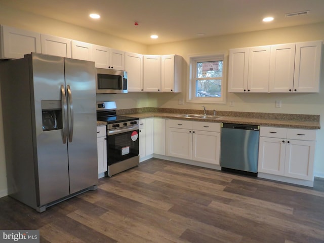 kitchen with stainless steel appliances, white cabinetry, dark wood-type flooring, and sink