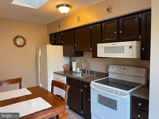 kitchen featuring dark brown cabinets, white appliances, sink, and light tile patterned floors