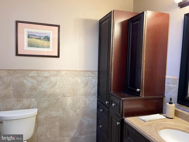 bathroom with vanity, toilet, and tile walls