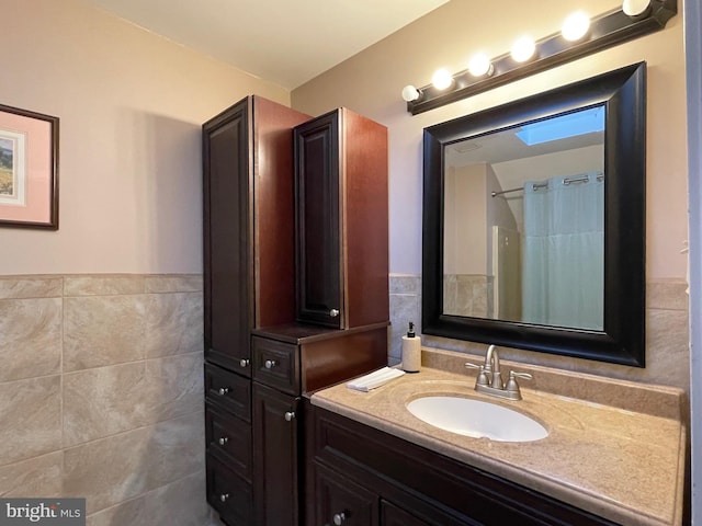 bathroom featuring a shower with curtain, vanity, and tile walls