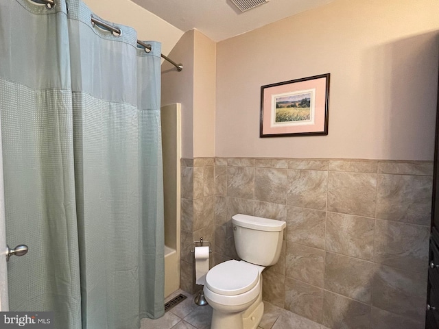 bathroom with tile patterned floors, shower / bath combo, tile walls, and toilet