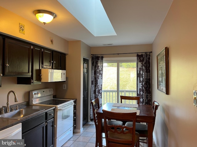 kitchen featuring a skylight, sink, white appliances, dark brown cabinets, and light tile patterned floors