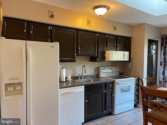 kitchen featuring white appliances, sink, light tile patterned floors, and a skylight