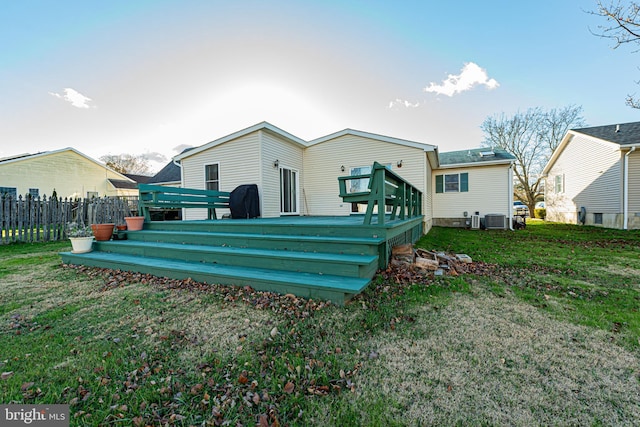 rear view of property featuring cooling unit, a lawn, and a wooden deck