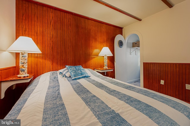 bedroom featuring beamed ceiling, carpet floors, and wooden walls