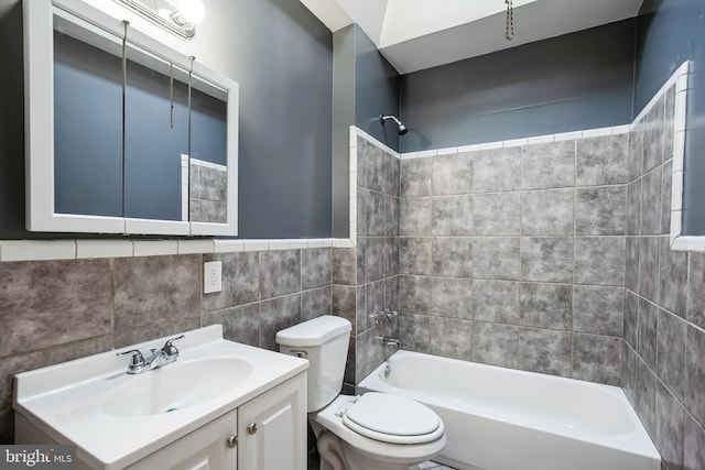 full bathroom featuring vanity, toilet, tiled shower / bath, and tile walls