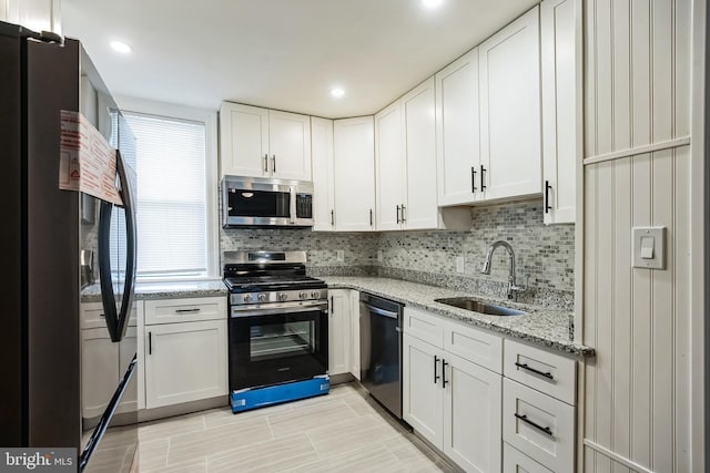 kitchen with white cabinetry, sink, light stone countertops, decorative backsplash, and appliances with stainless steel finishes