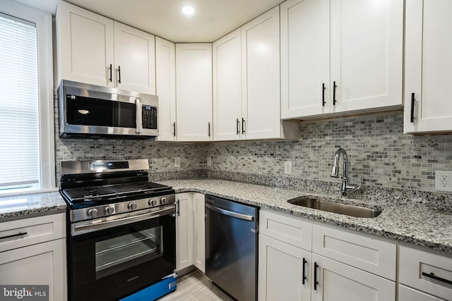 kitchen featuring decorative backsplash, white cabinetry, sink, and stainless steel appliances