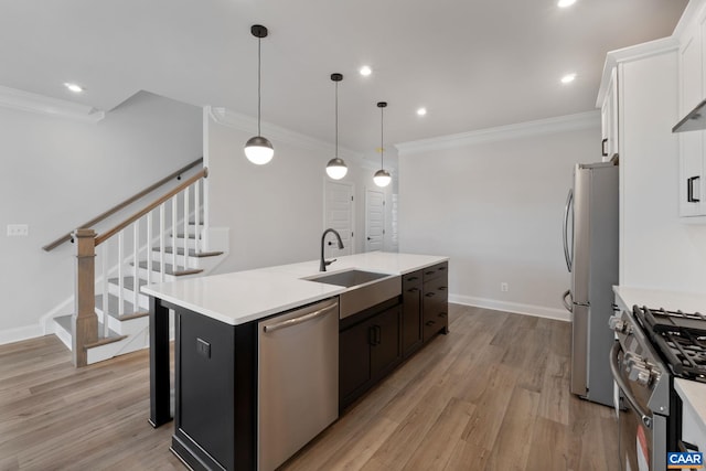 kitchen with white cabinets, sink, hanging light fixtures, an island with sink, and stainless steel appliances