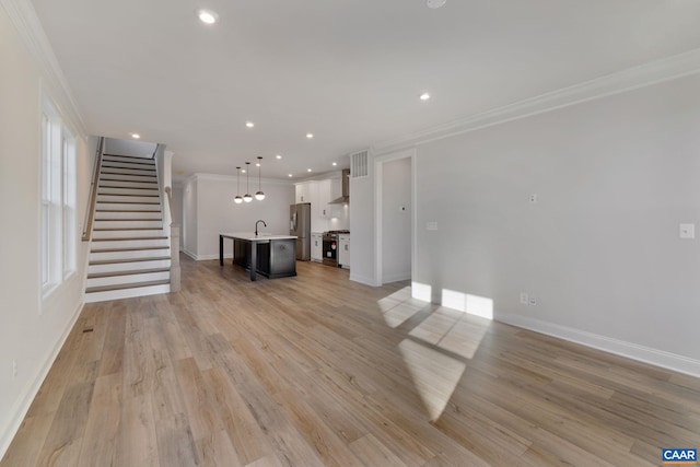 unfurnished living room featuring ornamental molding, sink, and light hardwood / wood-style flooring