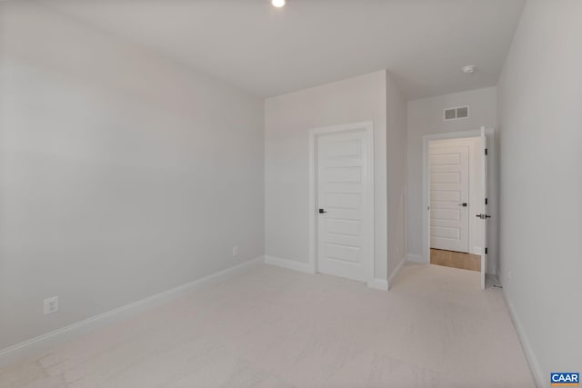 unfurnished bedroom featuring light carpet and a closet