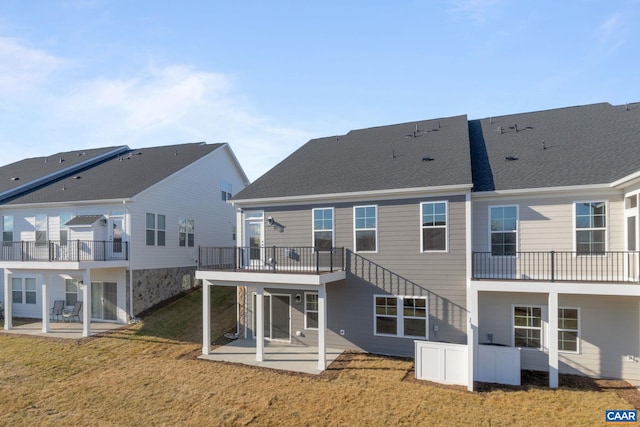 rear view of property featuring a yard, a patio, and a balcony