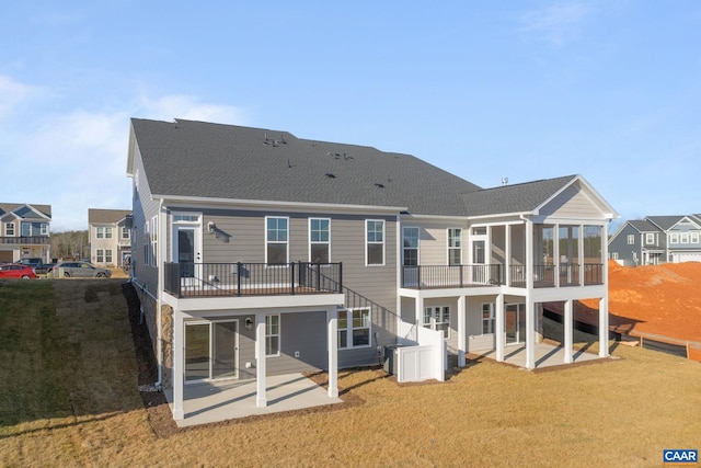 back of house featuring a yard, a patio, and a sunroom