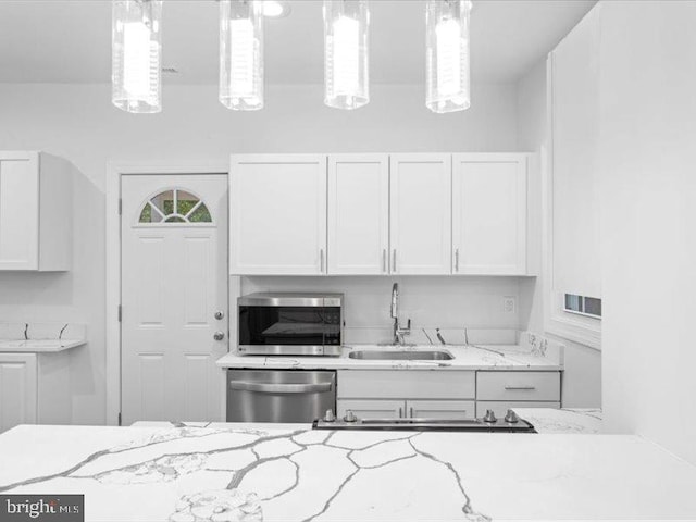 kitchen with white cabinetry, sink, hanging light fixtures, and appliances with stainless steel finishes