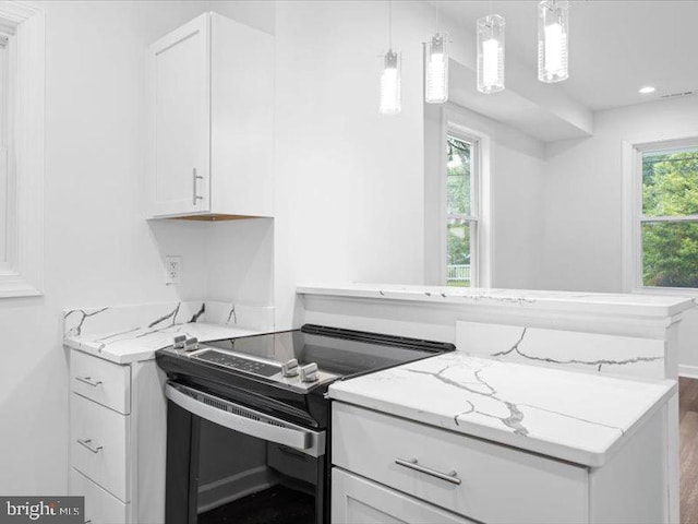 kitchen with electric range, light stone counters, white cabinets, and hanging light fixtures