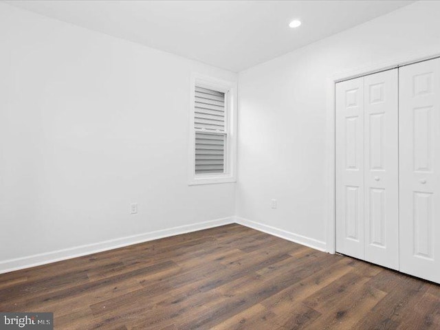 unfurnished bedroom featuring a closet and dark wood-type flooring