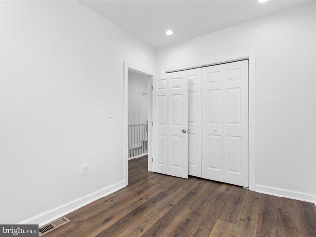 unfurnished bedroom featuring a closet and dark hardwood / wood-style floors