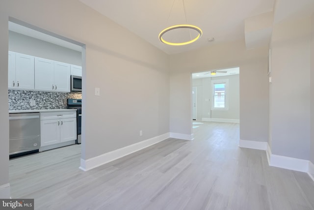 unfurnished dining area with ceiling fan and light wood-type flooring